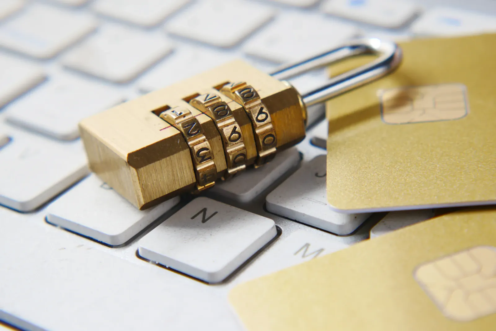 Candado dorado sobre un teclado junto a tarjetas con chip, que representa la seguridad del sistema financiero